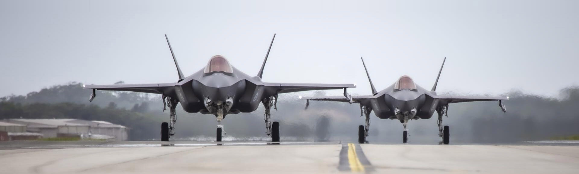 Two fighter jets, front-on, on a hot runway