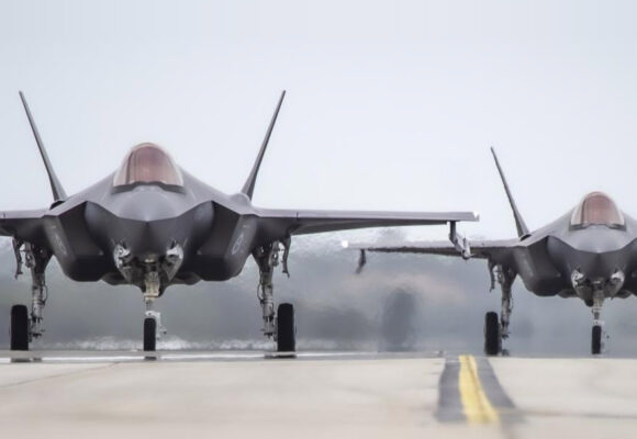 Two fighter jets, front-on, on a hot runway